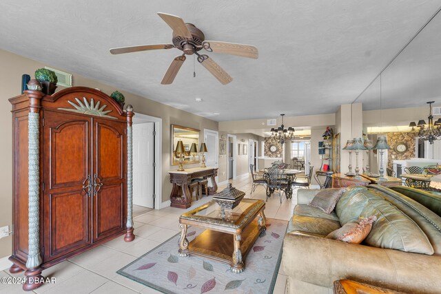 living room with ceiling fan with notable chandelier, a textured ceiling, and light tile patterned floors