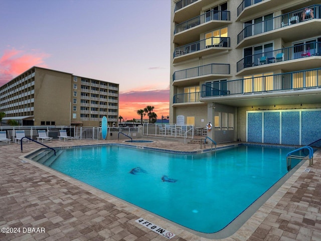 pool at dusk featuring a patio area