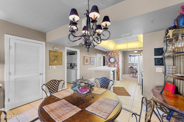 dining area with washer / dryer, a chandelier, and light tile patterned flooring