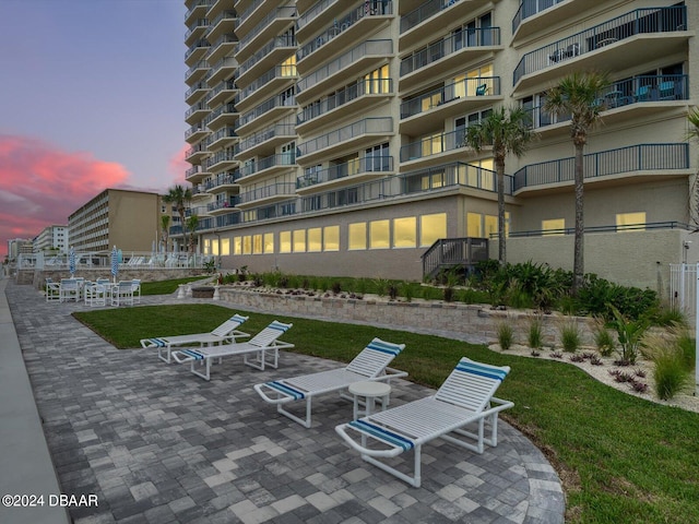 patio terrace at dusk with a yard and a balcony