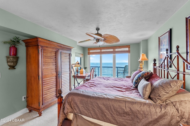 bedroom with a water view, ceiling fan, a textured ceiling, light colored carpet, and access to outside