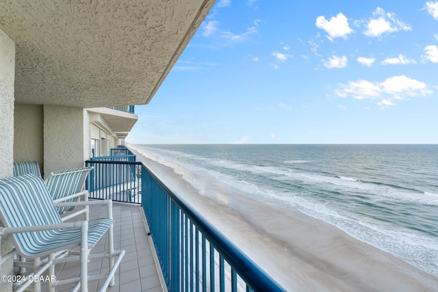 balcony with a water view and a view of the beach