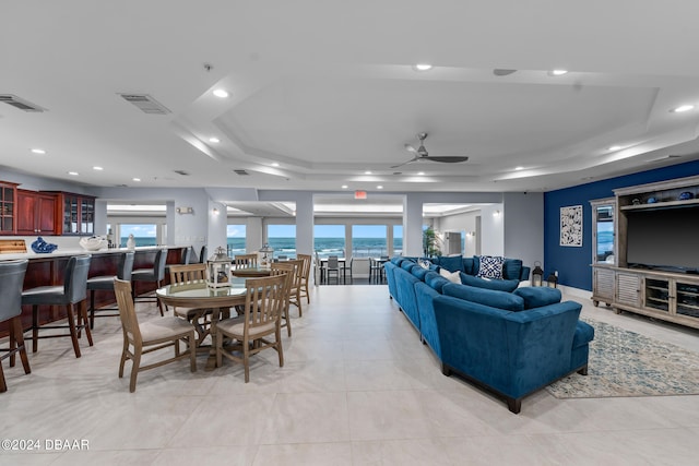 living room with ceiling fan and a raised ceiling