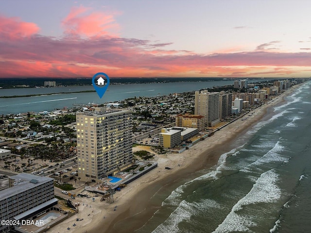 aerial view at dusk featuring a view of the beach and a water view