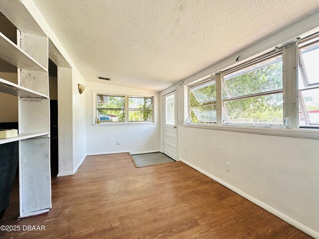 1228 Leon Ln, Daytona Beach, FL 32117 - unfurnished dining area featuring a textured ceiling, wood finished floors, lofted ceiling, baseboards, and plenty of natural light