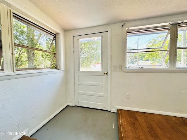 1228 Leon Ln, Daytona Beach, FL 32117 - doorway to outside featuring a textured ceiling, concrete floors, healthy amount of natural light, and baseboards