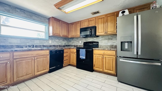 1228 Leon Ln, Daytona Beach, FL 32117 - kitchen with black appliances, a sink, tasteful backsplash, dark stone countertops, and brown cabinetry