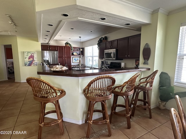 3651 S Central Ave Unit 101, Flagler Beach, FL 32136 - kitchen with appliances with stainless steel finishes, dark countertops, light tile patterned floors, a breakfast bar, and ornamental molding