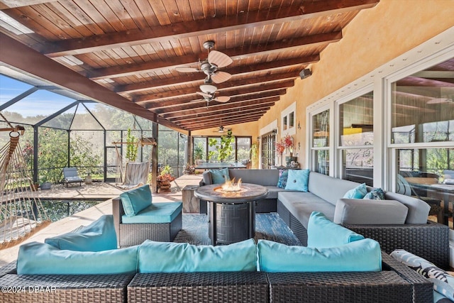 sunroom / solarium with ceiling fan, vaulted ceiling with beams, wooden ceiling, and a healthy amount of sunlight