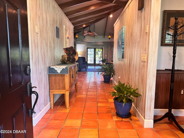 corridor with french doors, lofted ceiling with beams, wooden walls, and light tile patterned flooring