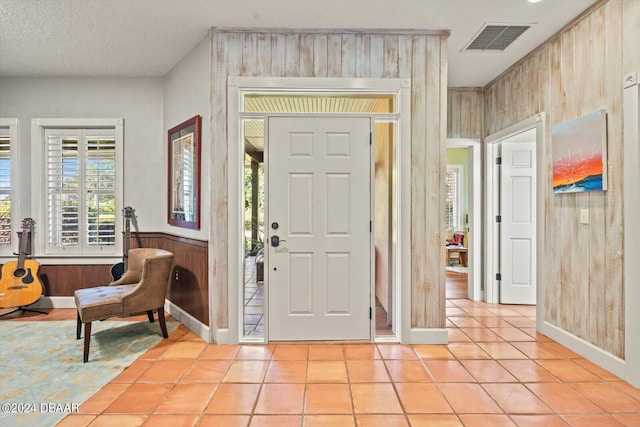 tiled foyer with a textured ceiling and wooden walls