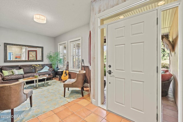 foyer entrance with a textured ceiling and light tile patterned flooring