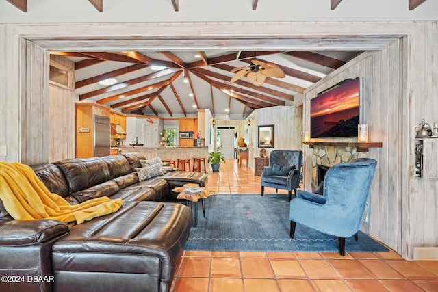 tiled living room featuring a stone fireplace, wood walls, vaulted ceiling with beams, and ceiling fan