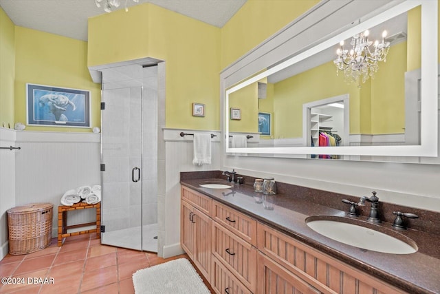 bathroom featuring a shower with door, vanity, a textured ceiling, an inviting chandelier, and tile patterned flooring