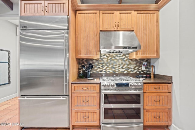 kitchen featuring light tile patterned flooring, high end appliances, decorative backsplash, and exhaust hood