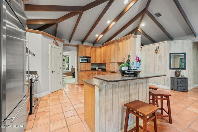 kitchen with stainless steel appliances, light tile patterned floors, a kitchen breakfast bar, light brown cabinets, and lofted ceiling with beams