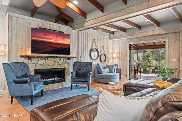 tiled living room with wood walls, ceiling fan, beamed ceiling, and a fireplace