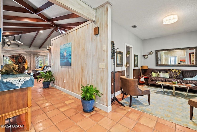 interior space featuring wood walls, a textured ceiling, light tile patterned floors, and vaulted ceiling with beams