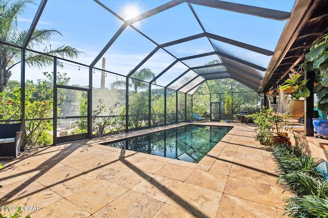 view of swimming pool featuring glass enclosure and a patio