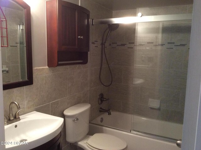 full bathroom with tile walls, sink, toilet, and combined bath / shower with glass door