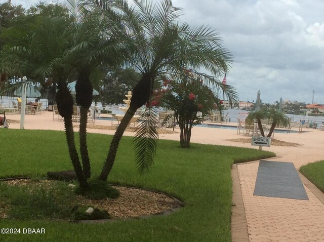 view of home's community with a lawn, a pool, and a water view