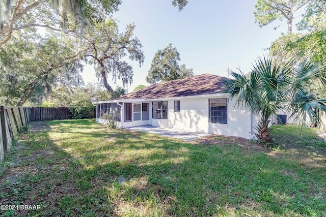 back of house featuring a yard, a patio area, and a sunroom