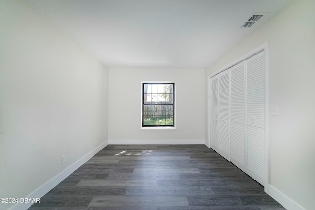 unfurnished bedroom featuring dark hardwood / wood-style flooring and a closet