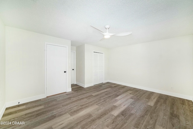 empty room featuring ceiling fan, dark wood-type flooring, and a textured ceiling