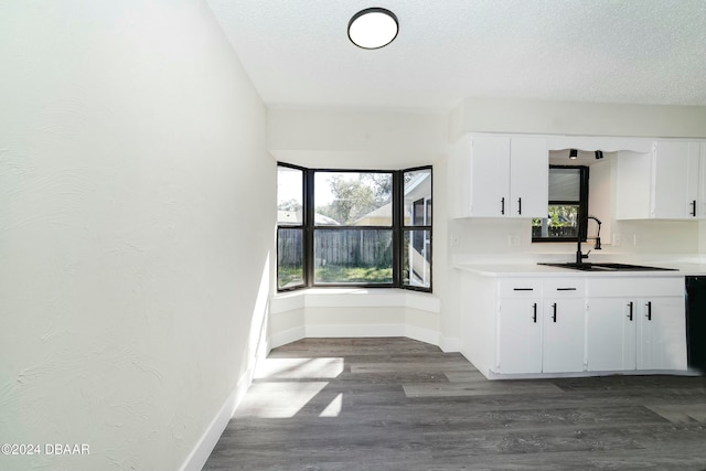 kitchen featuring dark hardwood / wood-style floors, dishwasher, sink, white cabinets, and a textured ceiling