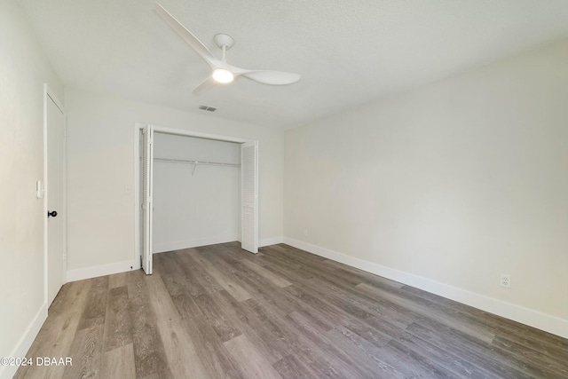 unfurnished bedroom with ceiling fan, hardwood / wood-style floors, a closet, and a textured ceiling