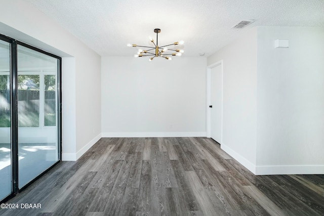 empty room with dark hardwood / wood-style floors, a textured ceiling, and a notable chandelier