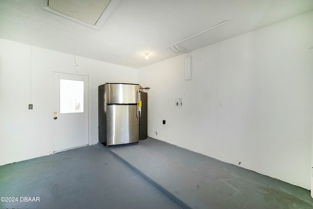 garage with electric water heater and stainless steel refrigerator