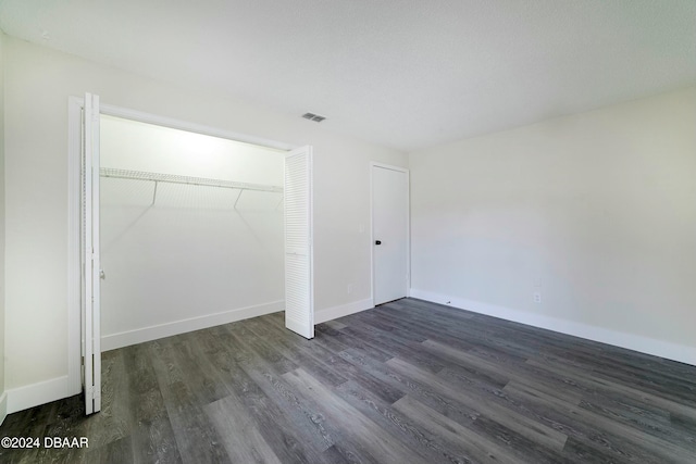 unfurnished bedroom with dark hardwood / wood-style flooring and a closet