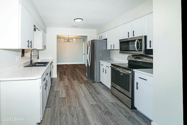 kitchen featuring sink, white cabinetry, a textured ceiling, appliances with stainless steel finishes, and hardwood / wood-style floors