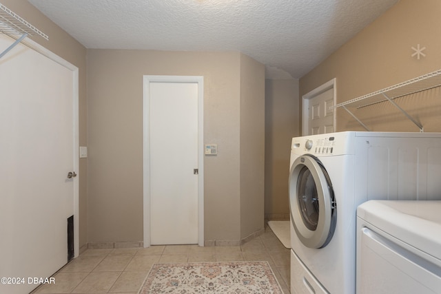 laundry area with light tile patterned floors, a textured ceiling, and washer and clothes dryer