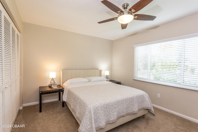 bedroom featuring ceiling fan, light carpet, and a closet