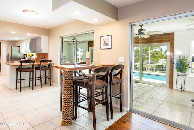 bar featuring stainless steel refrigerator, ceiling fan, and light tile patterned floors