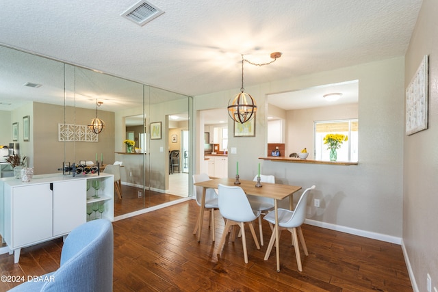 dining area with a textured ceiling, dark hardwood / wood-style floors, and an inviting chandelier