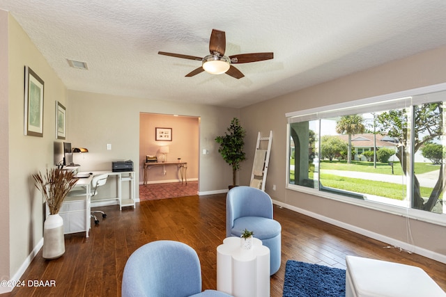 living area featuring a textured ceiling, dark hardwood / wood-style flooring, and ceiling fan