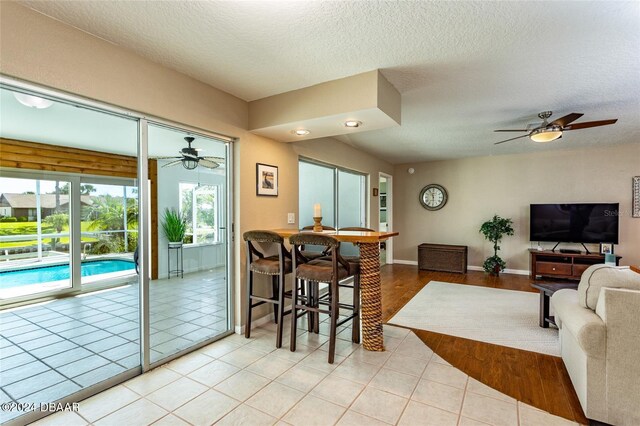 tiled living room featuring ceiling fan and a textured ceiling