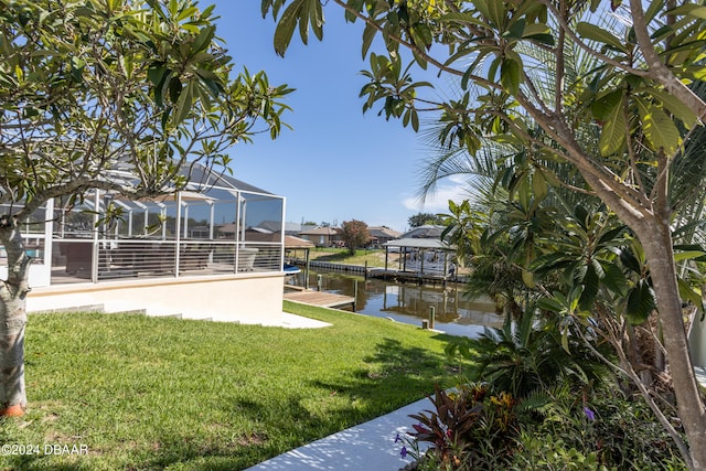 view of yard featuring a lanai, a water view, and a dock