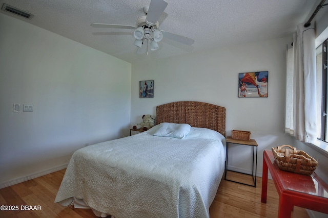 bedroom with ceiling fan, light hardwood / wood-style floors, and a textured ceiling