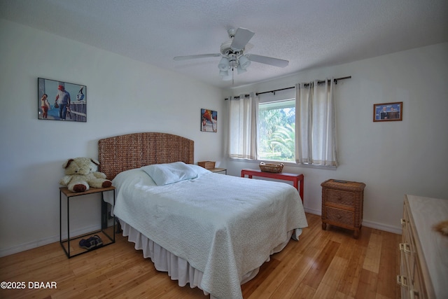 bedroom featuring ceiling fan, light hardwood / wood-style flooring, and a textured ceiling