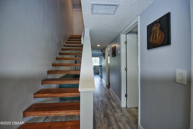 staircase with hardwood / wood-style flooring and a textured ceiling