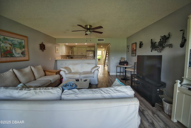 living room featuring hardwood / wood-style flooring, a textured ceiling, and ceiling fan