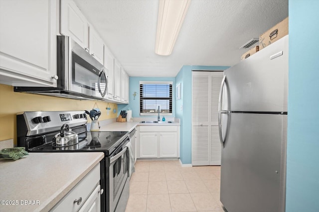 3100 Ocean Shore Blvd Unit 5020, Ormond Beach, FL 32176 - kitchen with appliances with stainless steel finishes, a sink, light countertops, white cabinetry, and a textured ceiling