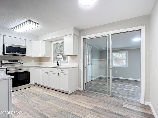 kitchen featuring light countertops, stainless steel appliances, white cabinets, and a sink