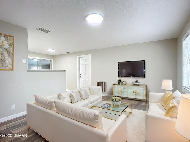 living area featuring baseboards, wood finished floors, and visible vents