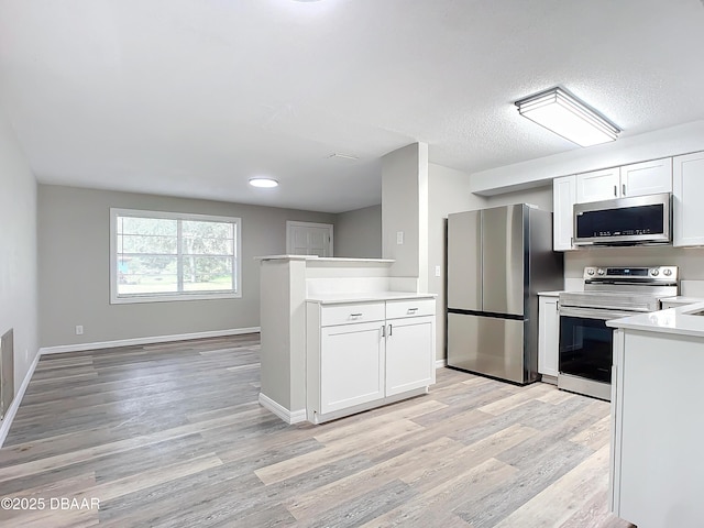kitchen with light countertops, light wood-style flooring, appliances with stainless steel finishes, and white cabinetry