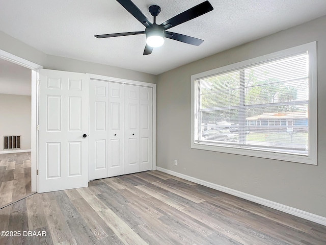 unfurnished bedroom featuring visible vents, light wood finished floors, baseboards, and a closet